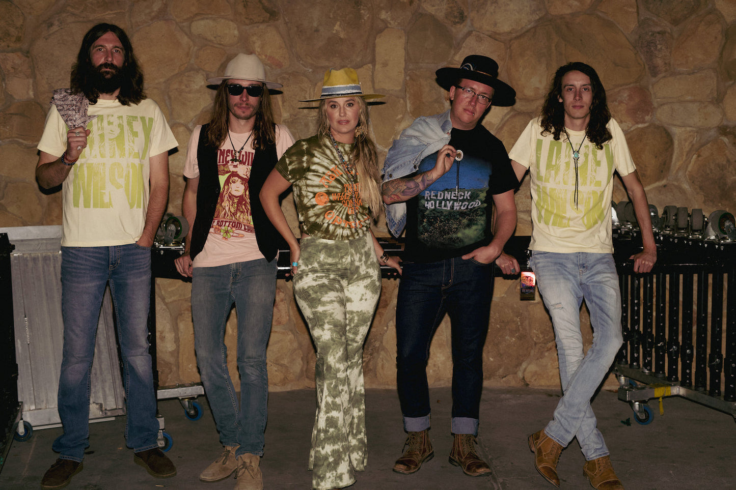 Five-person rock band posing together in eclectic outfits including hats and casual wear.