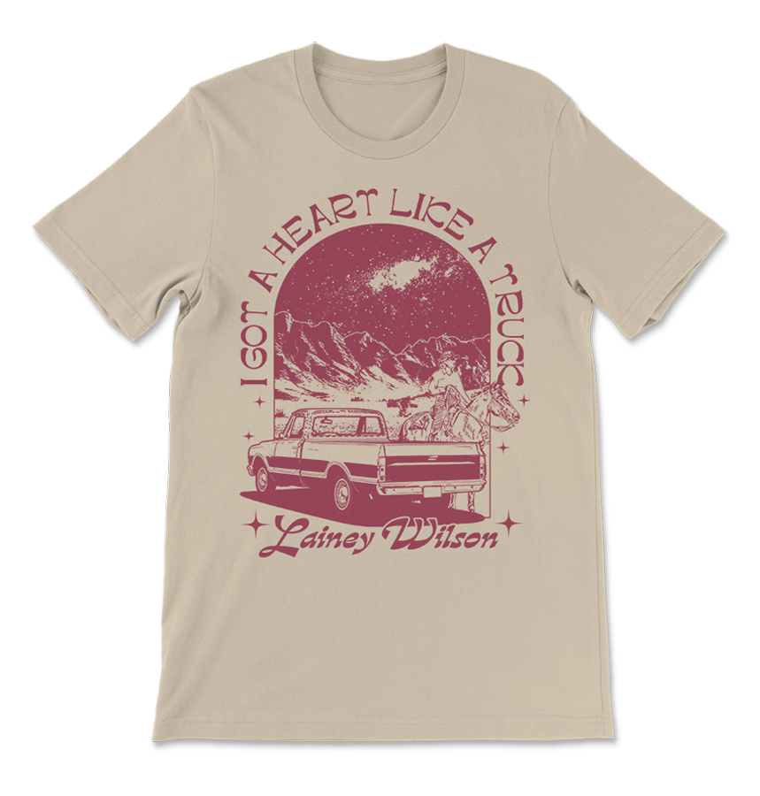 Beige t-shirt with a red vintage-style graphic design featuring a truck, mountains, and text.