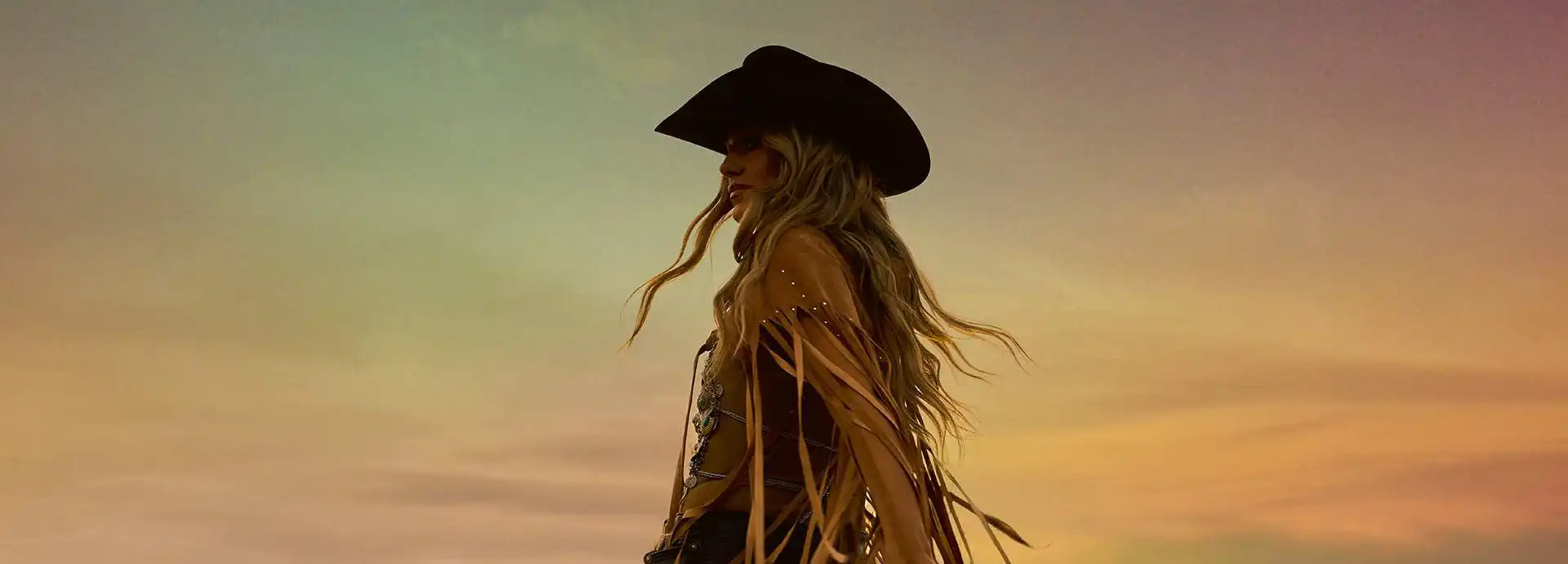 A person in a cowboy hat and fringed top.