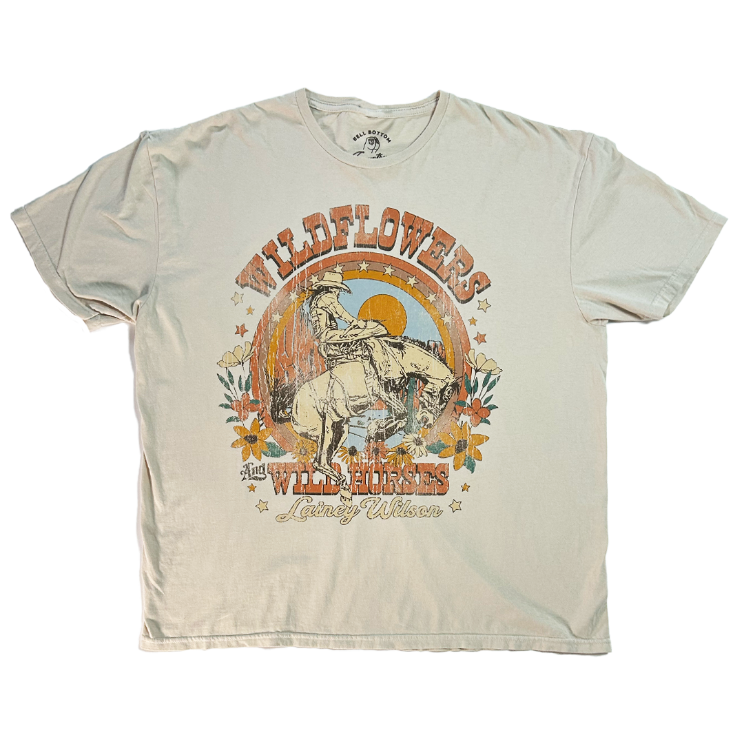 Beige t-shirt with a vintage-style cowboy and horse graphic design featuring ’Wildflowers and Wild Horses’ text.